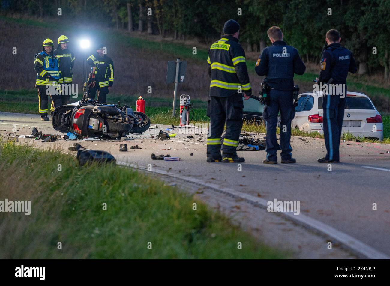 03. Oktober 2022, Bayern, Geiselhöring: Rettungskräfte stehen vor einem komplett zerstörten Motorrad neben einem Auto. Bei einem Unfall zwischen einem Auto und einer Gruppe von Motorradfahrern starb einer der Motorradfahrer. Ein zweiter Motorradfahrer wurde schwer verletzt ins Krankenhaus gebracht. Foto: Armin Weigel/dpa - ACHTUNG: Kennzeichen(e) wurden aus rechtlichen Gründen verpixelt Stockfoto