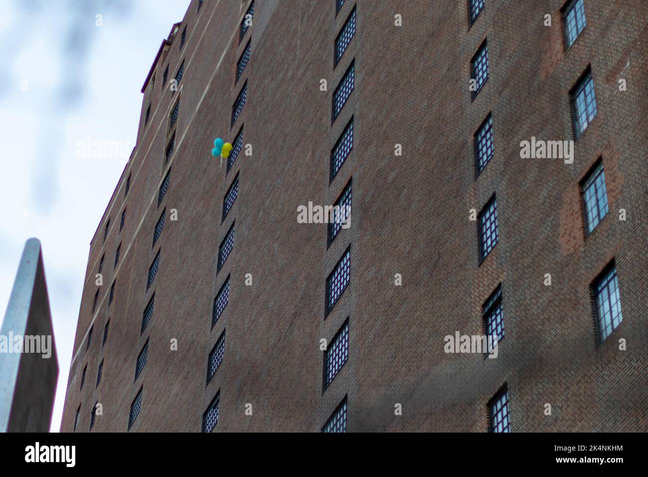 Ein altes Wohnhaus und blau gelbe Ballons fliegen hoch Stockfoto