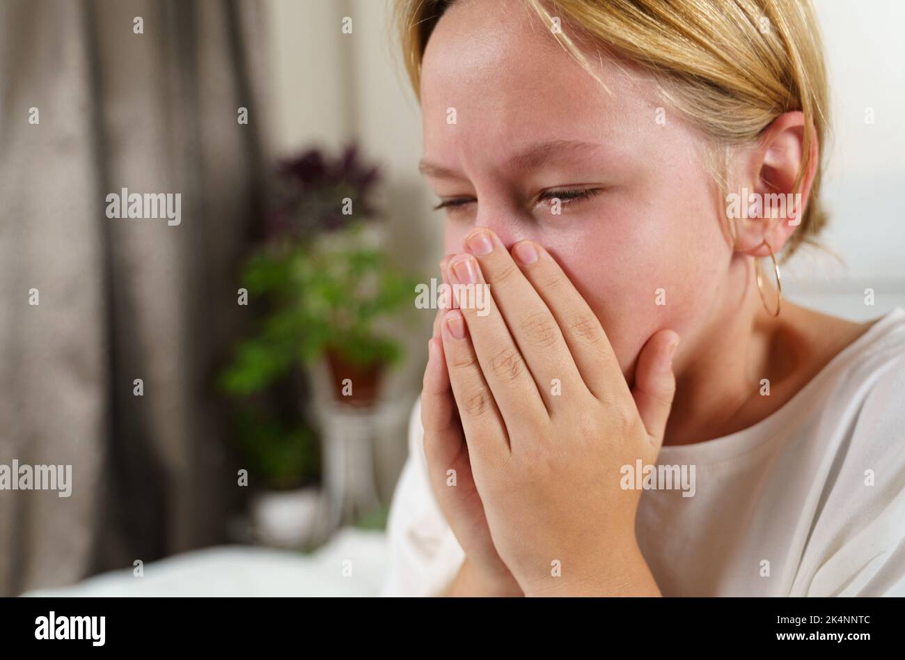 Das kranke Mädchen hustet schwer und bedeckt ihren Mund mit ihren Händen. Nahaufnahme. Medizin und Gesundheitskonzept. Stockfoto