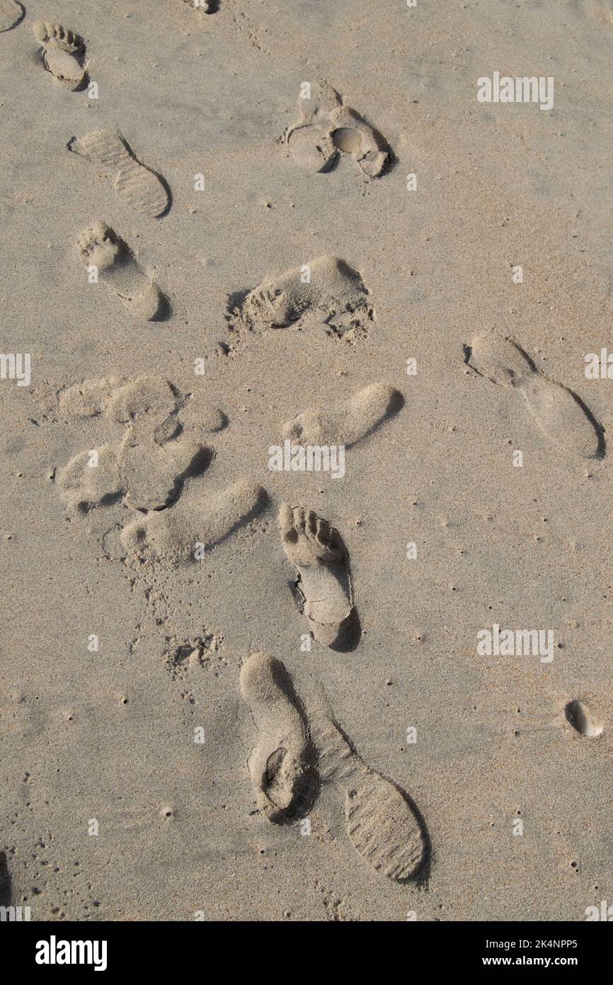 Füße drucken auf dem Sand am Strand, Strandspazierschritte Texturen auf dem Sand. Erinnerungen und Konzepte der psychischen Gesundheit. Spaziergang am Strand. Ungeerzählte Geschichten. Stockfoto
