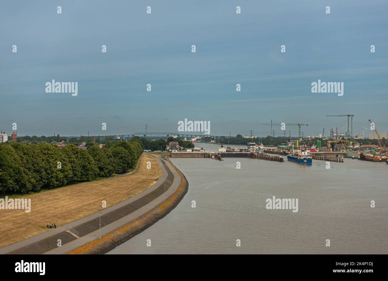 Brunsbuttel, Deutschland - 12. Juli 2022: Weite Landschaft unter teilweise wolkig-blauem Himmel der Kieler Kanal Schleusen mit eindringendem Schiff. Graues Nordsee-Wasser U Stockfoto