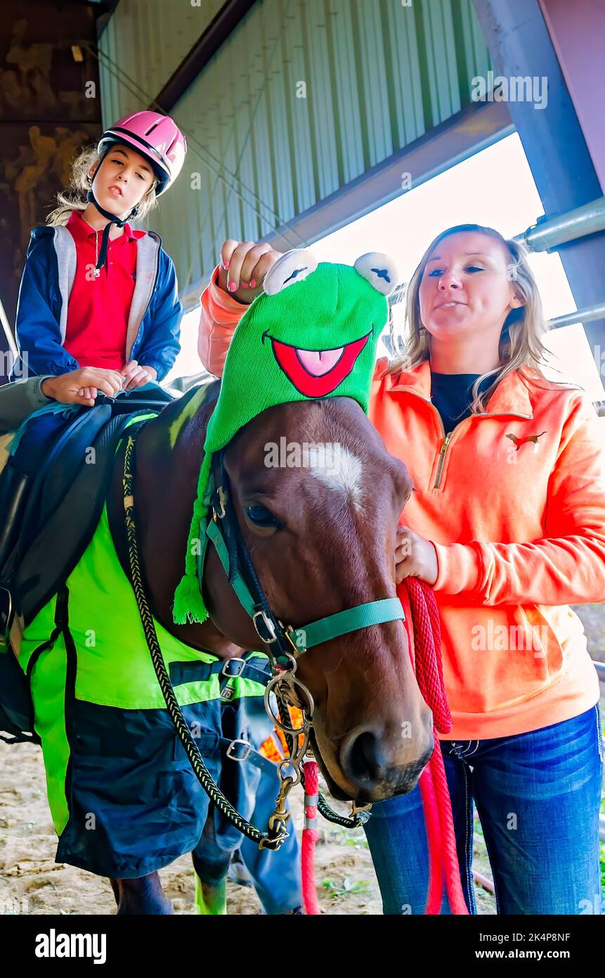 Ein Mädchen sitzt mit einem Therapiepferd auf einer Halloween-Kostümparty für Reiter im therapeutischen Reitprogramm in West Point, Mississippi. Stockfoto