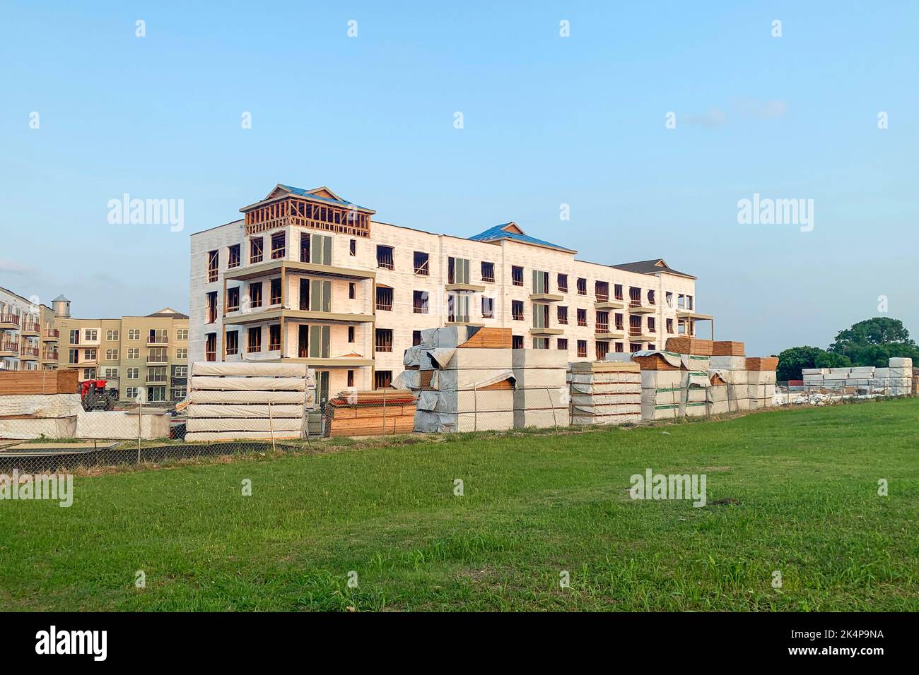 Außenaufnahme von modernen Mehrfamilienhäusern in einem grünen Wohngebiet, Haus im Bau, umgeben von einer großen Menge an Holz. Stockfoto