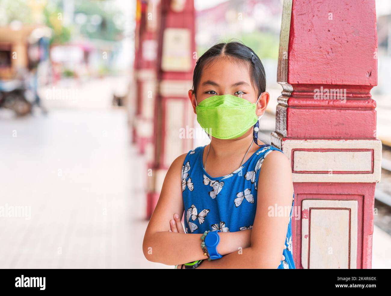 Portrait of adorable Kind Mädchen trägt Gesichtsmaske, um Virus zu schützen, während der Reise in Thailand am Hau hin Bahnhof, gekreuzten Arm auf der Brust, Augen sehen Stockfoto