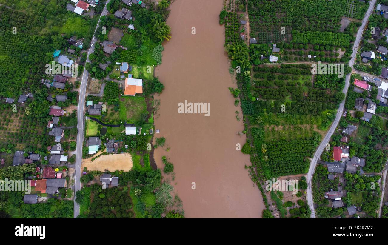 Luftaufnahme des Flusses, der nach starken Regenfällen und Überschwemmungen von Feldern in ländlichen Dörfern fließt. Draufsicht auf landwirtschaftliche Flächen, die von Regenzeit betroffen sind Stockfoto