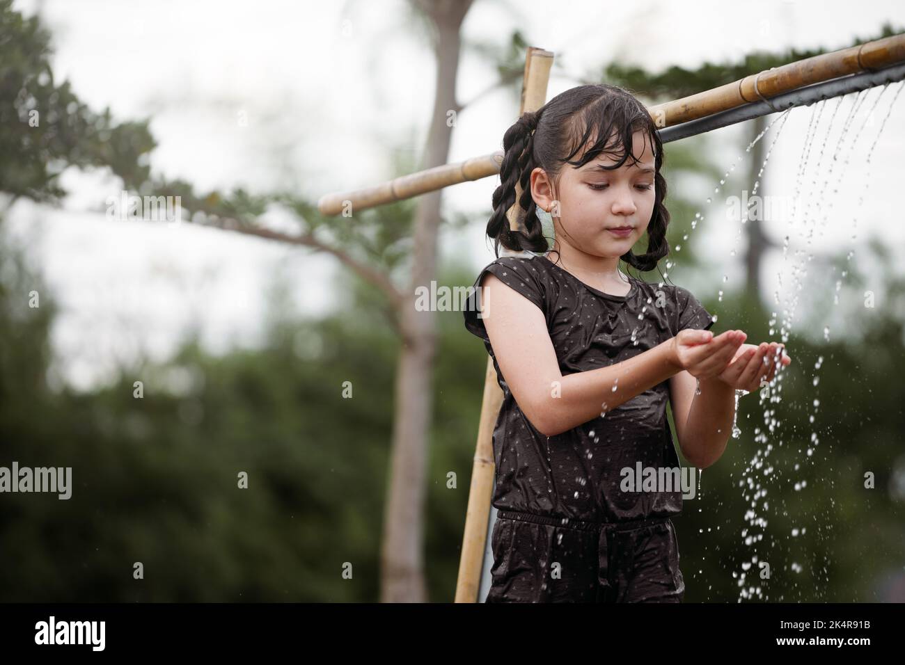 Kind Mädchen hat Spaß spielen im Wasser im Freien. Stockfoto