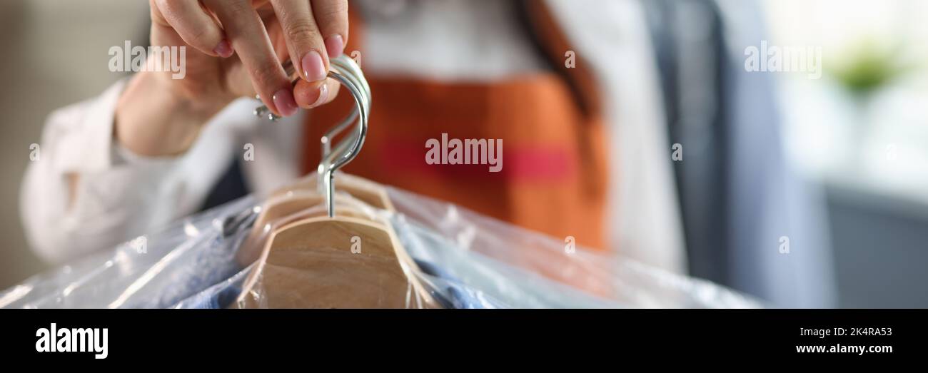 Die Dame an der Rezeption hält saubere Anzug aus der Nähe, nachdem sie trocken geputzt wurde Stockfoto