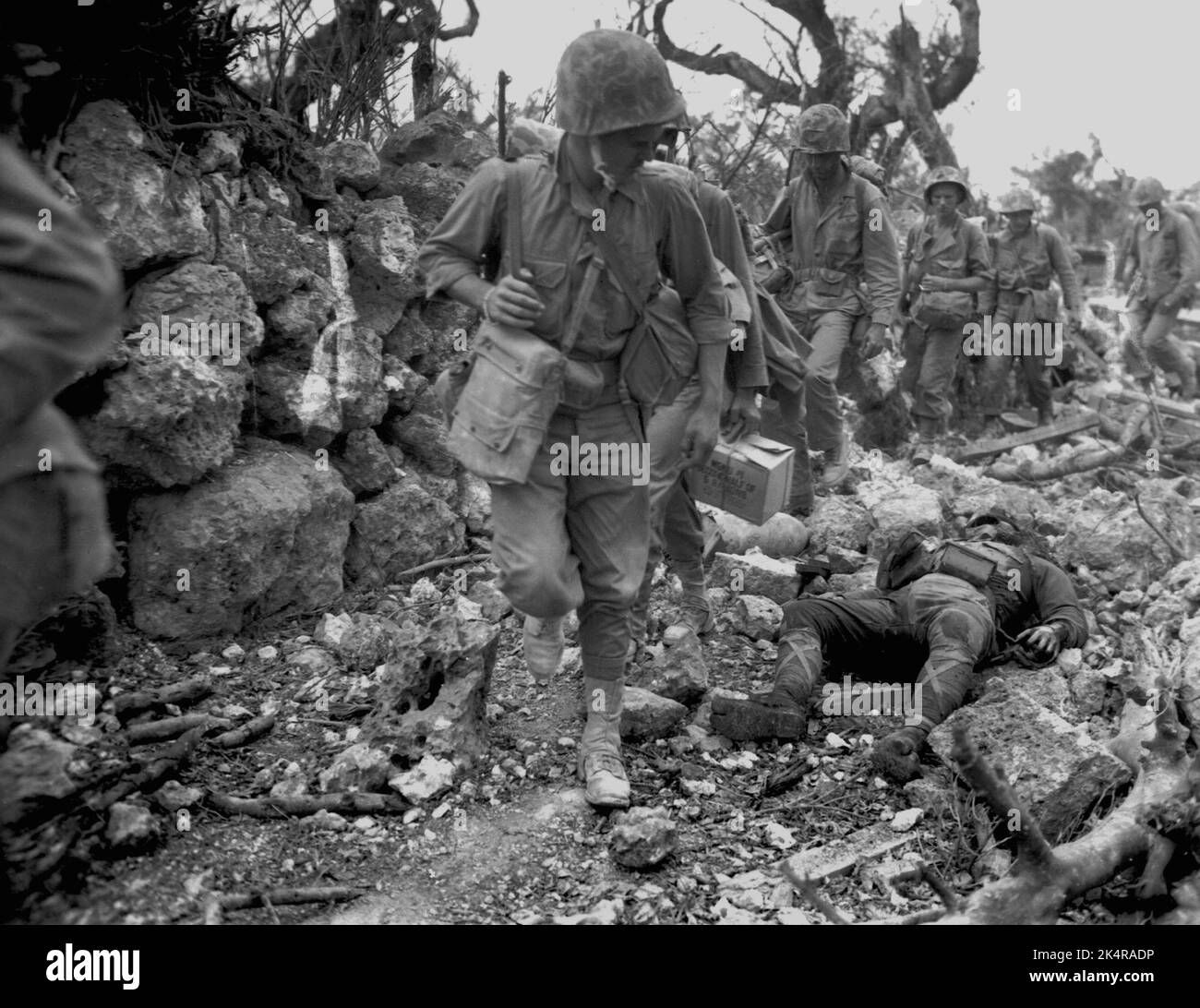 OKINAWA, PAZIFISCHER OZEAN - 1945. April - US-Marineinfanteristen passieren ein kleines Dorf, in dem japanische Soldaten nach dem Kampf gegen japanische Truppen auf Okina tot lagen Stockfoto