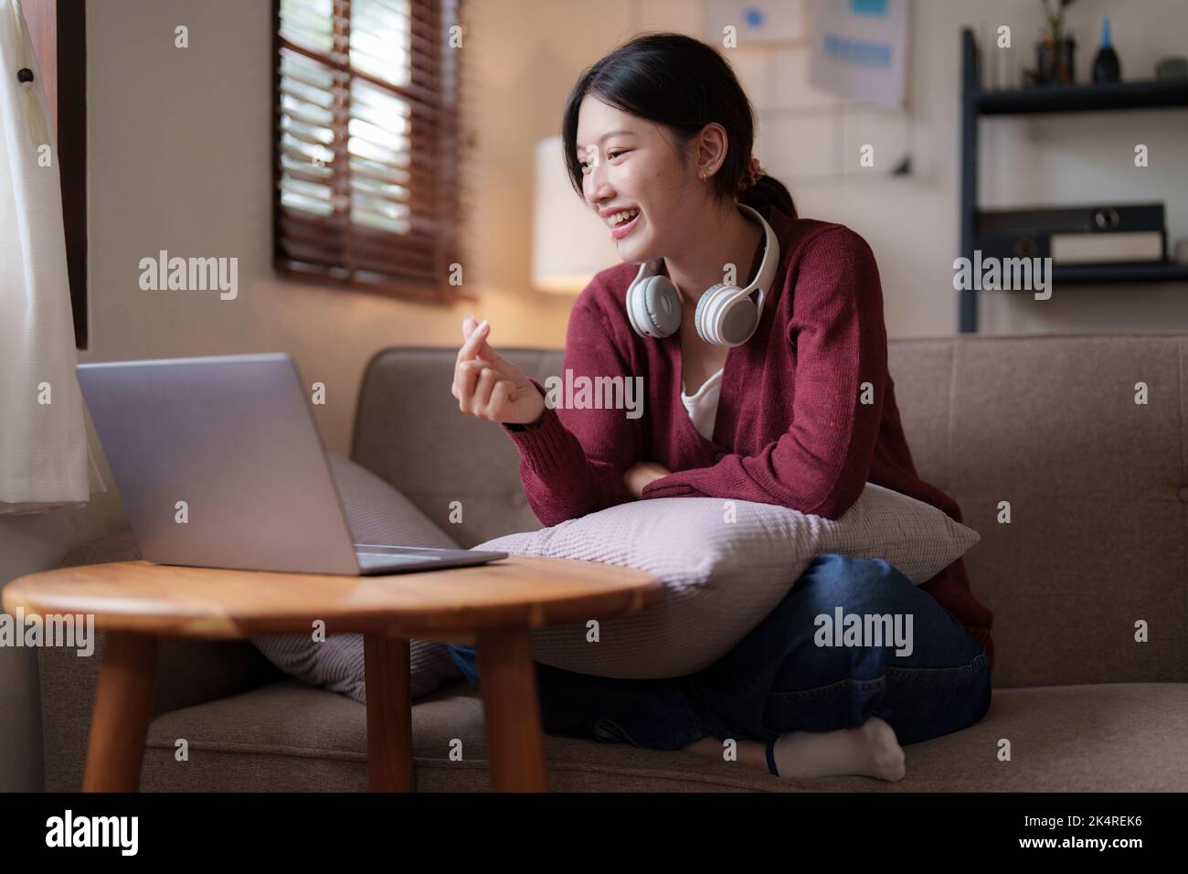 Attraktive lächelnde junge Frau Videoanruf von Laptop auf Sofa zu Hause. Lifestyle-Konzept Stockfoto