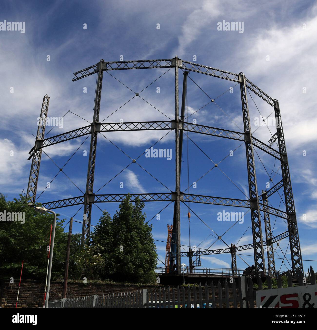Die Skelett- und Gitterstahlarbeiten des teilweise demontierten Gashalters ragen im Juni 2022 in Keighley vor blauem Himmel hervor Stockfoto