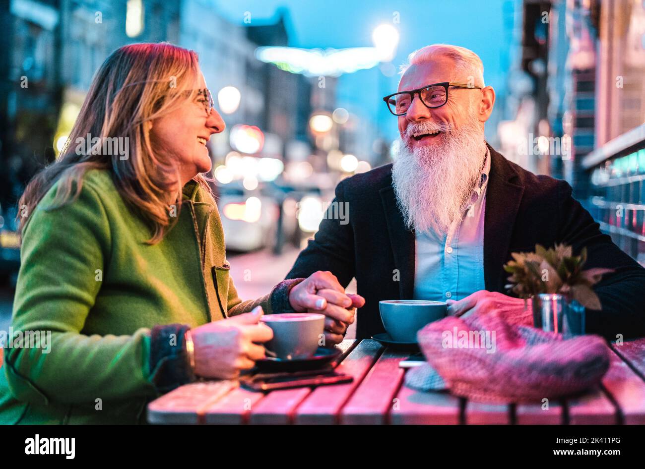 Hipster Rentnerehepaar verliebt sich in Cappuccino in der Cafeteria im Freien - fröhliches, älteres Lifestyle-Konzept mit Frau und Mann, die Spaß daran haben Stockfoto