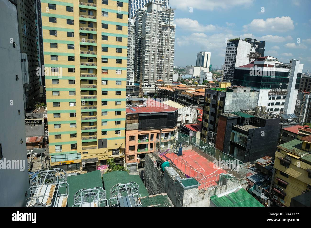 Manila, Philippinen - 2022. März: Blick auf Wolkenkratzer neben einem Basketballplatz in Manila am 20. März 2022 auf der Insel Luzon, Philippinen. Stockfoto