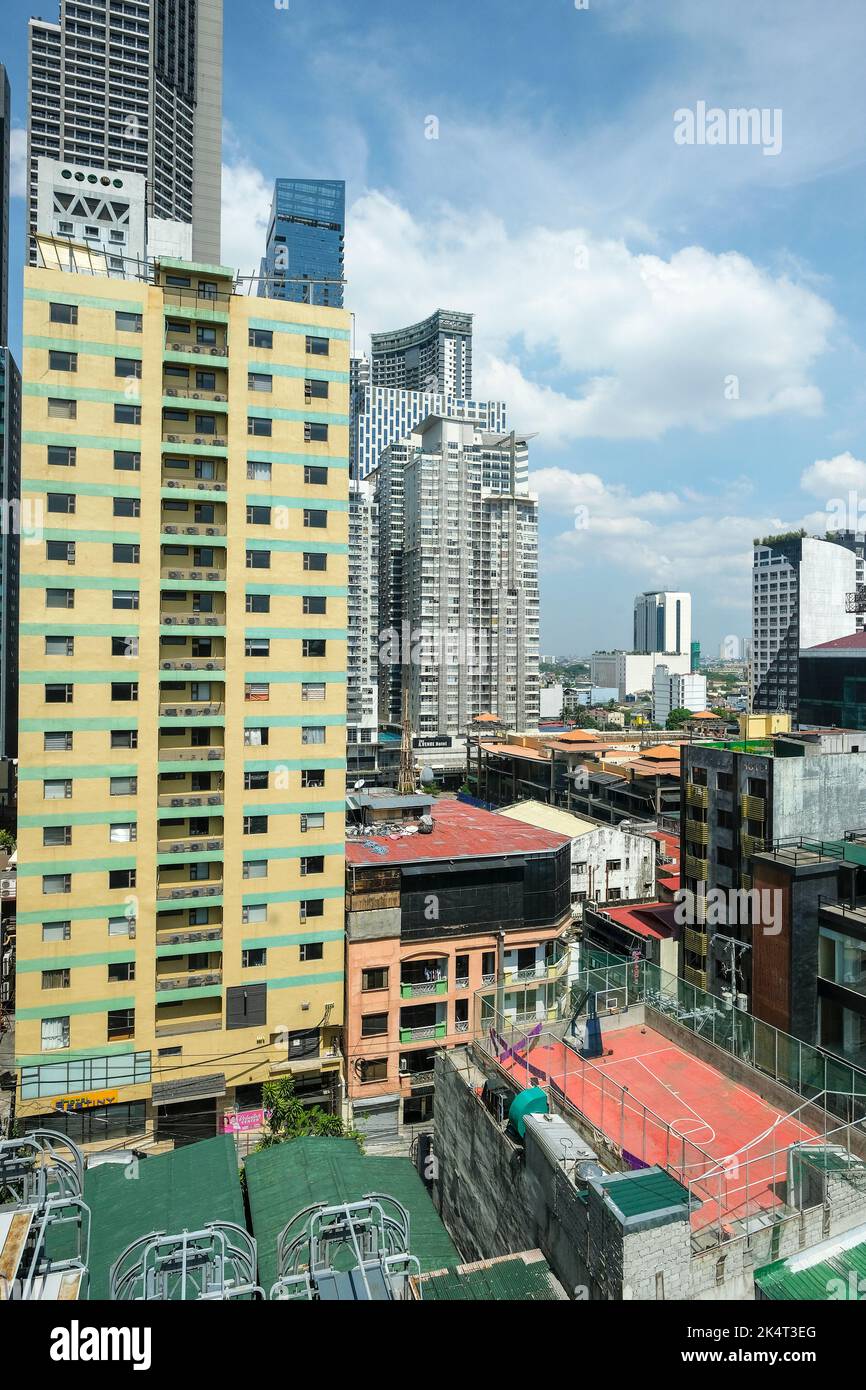 Manila, Philippinen - 2022. März: Blick auf Wolkenkratzer neben einem Basketballplatz in Manila am 20. März 2022 auf der Insel Luzon, Philippinen. Stockfoto