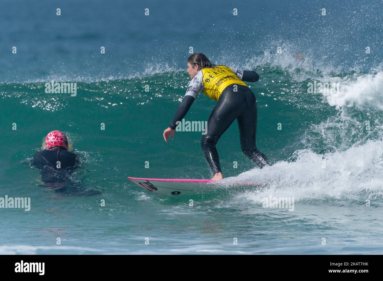 Ein Surfer bei einer beinahe-Kollision mit einem anderen Surfer, der bei Fistral in Newquay in Cornwall in Großbritannien einen Schutzhelm trägt. Stockfoto