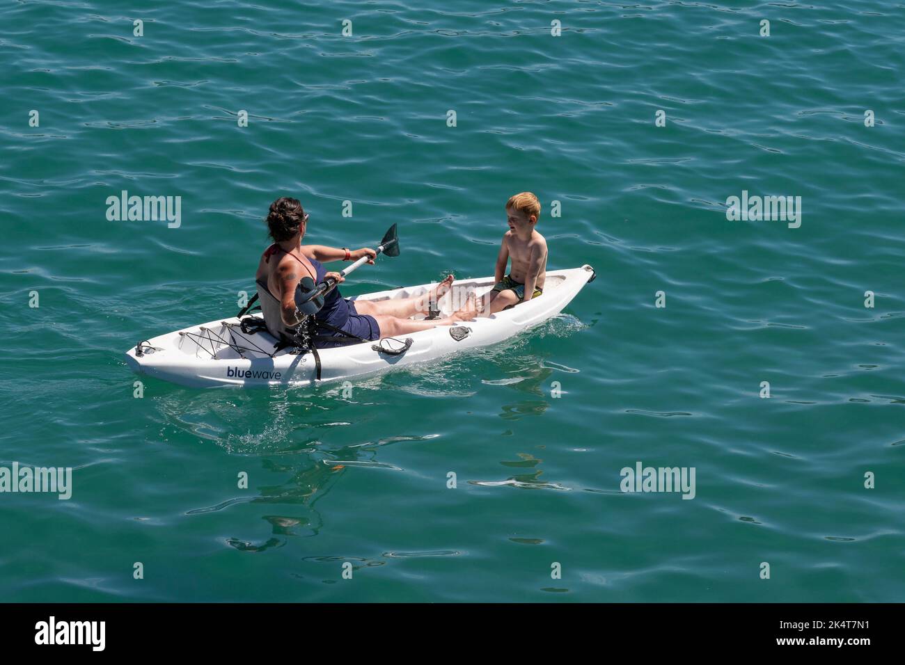 Eine Mutter und ein Kind sitzen auf einem Kajak in Newquay Bay in Cornwall in England im Vereinigten Königreich. Stockfoto