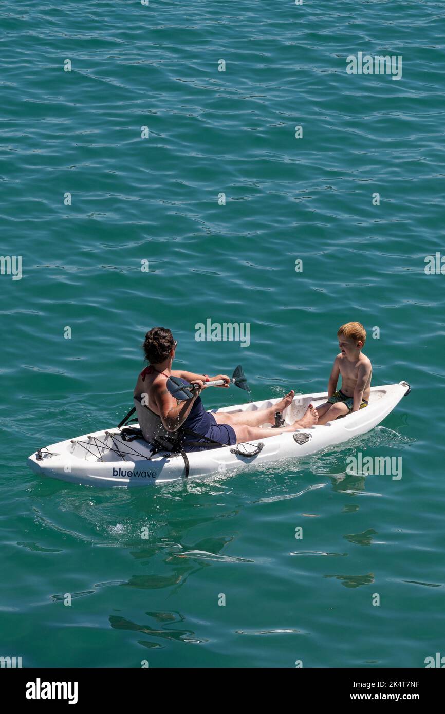 Eine Mutter und ein Kind sitzen auf einem Kajak in Newquay Bay in Cornwall in England im Vereinigten Königreich. Stockfoto