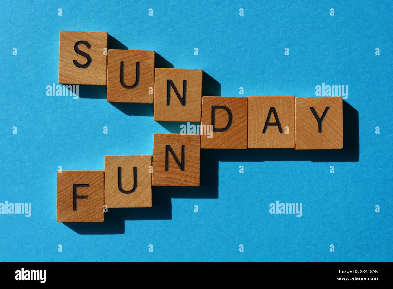 Sonntag, Funday, Wörter in Holzbuchstaben isoliert auf blauem Hintergrund Stockfoto