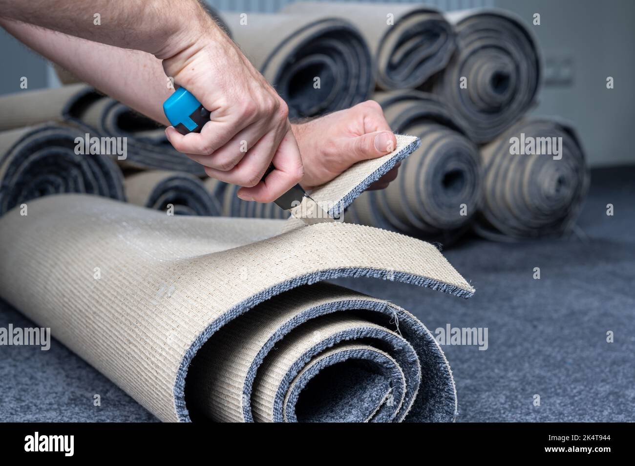 Handwerker schneidet einen neuen Teppich mit einem Teppichschneider. Stockfoto