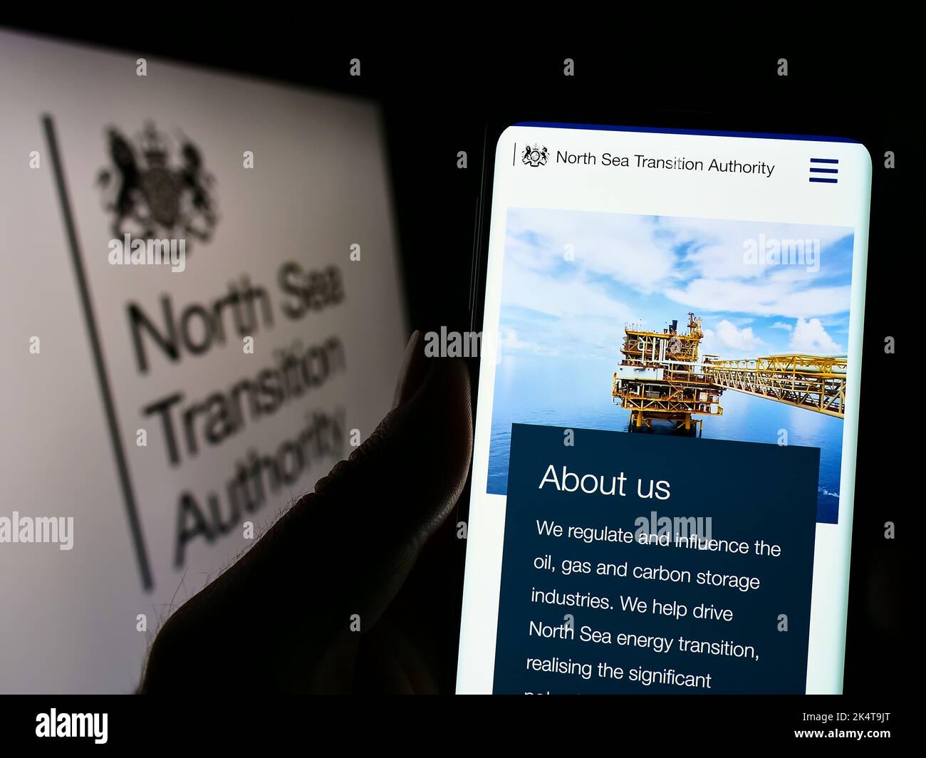 Person mit Mobiltelefon und Website der britischen North Sea Transition Authority (NSTA) auf dem Bildschirm mit Logo. Konzentrieren Sie sich auf die Mitte des Telefondisplays. Stockfoto