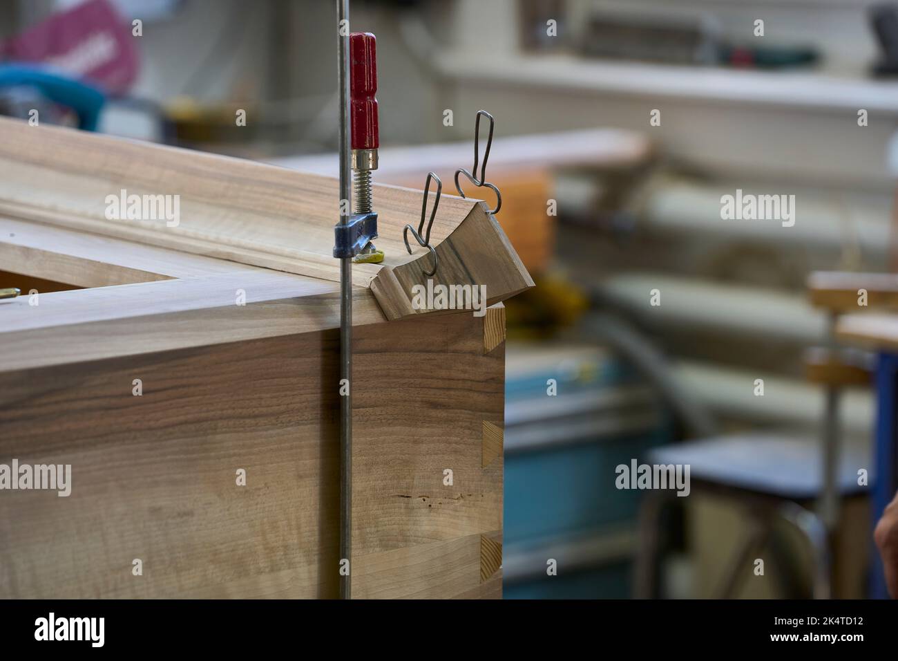 Ein Holzsockel wird mit Einer Schraubklemme an Einen Barockschrank geklebt. Russikon, Schweiz Stockfoto