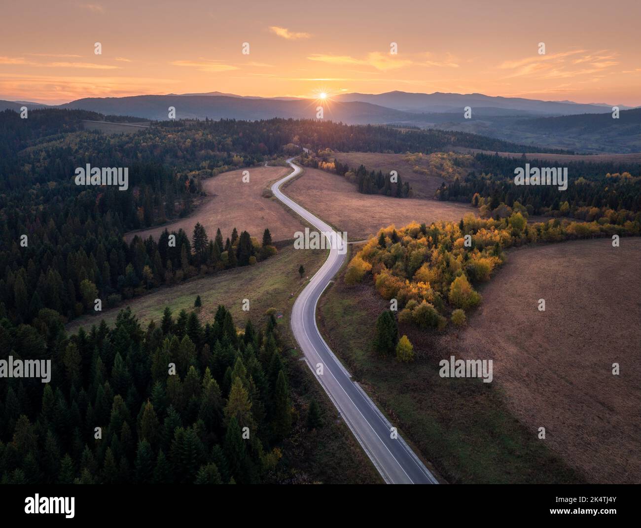 Luftaufnahme der Bergstraße im Herbstwald bei Sonnenuntergang Stockfoto