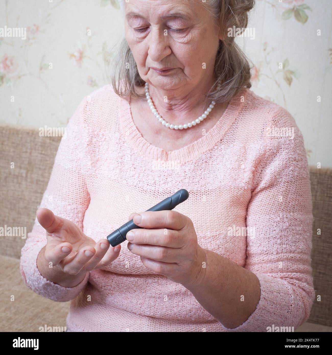 Ältere Frau, die den Blutzuckerspiegel mit Glucometer überprüft. Nahaufnahme einer alten Person mit Diabetes. Diabetesbehandlung für ältere Menschen. Stockfoto