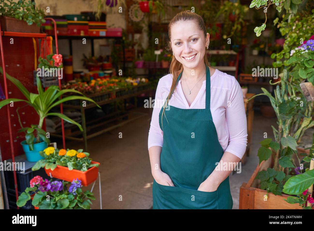 Zufriedene junge Frau als Floristin und Fachverkäuferin im Blumenladen der Baumschule Stockfoto