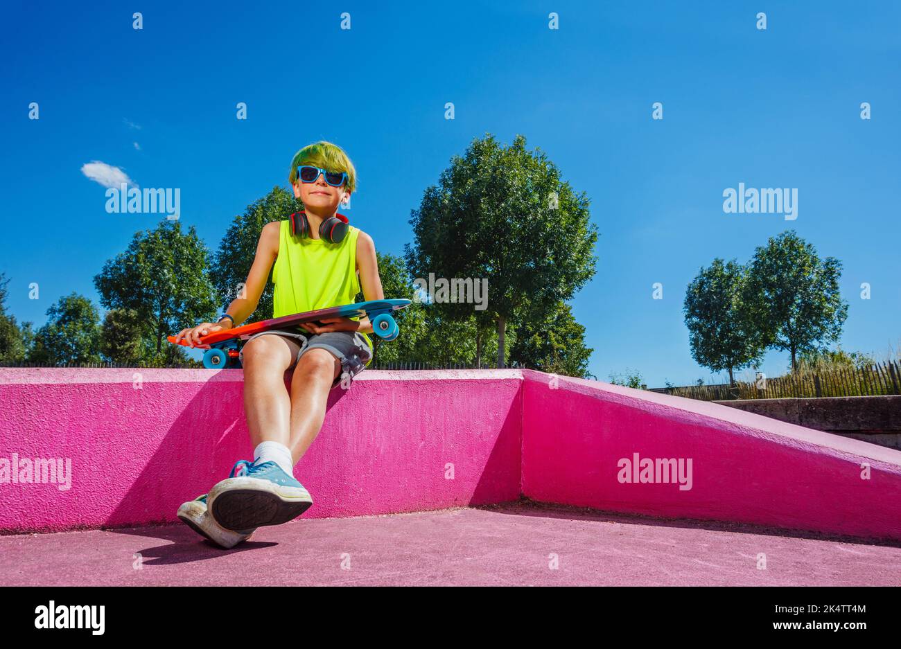 Boy mit grünen Haaren und Skateboard sitzen auf Rampe, Low-Angle-Ansicht Stockfoto