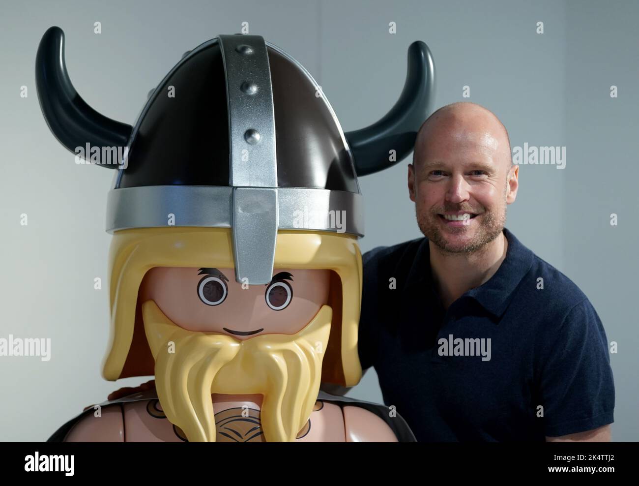 Hamburg, Deutschland. 04. Oktober 2022. Der Künstler Oliver Schaffer steht in der Sonderausstellung 'Playmobil - Archäologische Zeitreise' im Archäologischen Museum neben einer überdimensionalen Figur des Wikinger Playmobil. Im Archäologischen Museum Hamburg ist von Oktober 5 bis April 2 erstmals Deutschlands größte Playmobil-Sammlung zu sehen. Kredit: Marcus Brandt/dpa/Alamy Live Nachrichten Stockfoto
