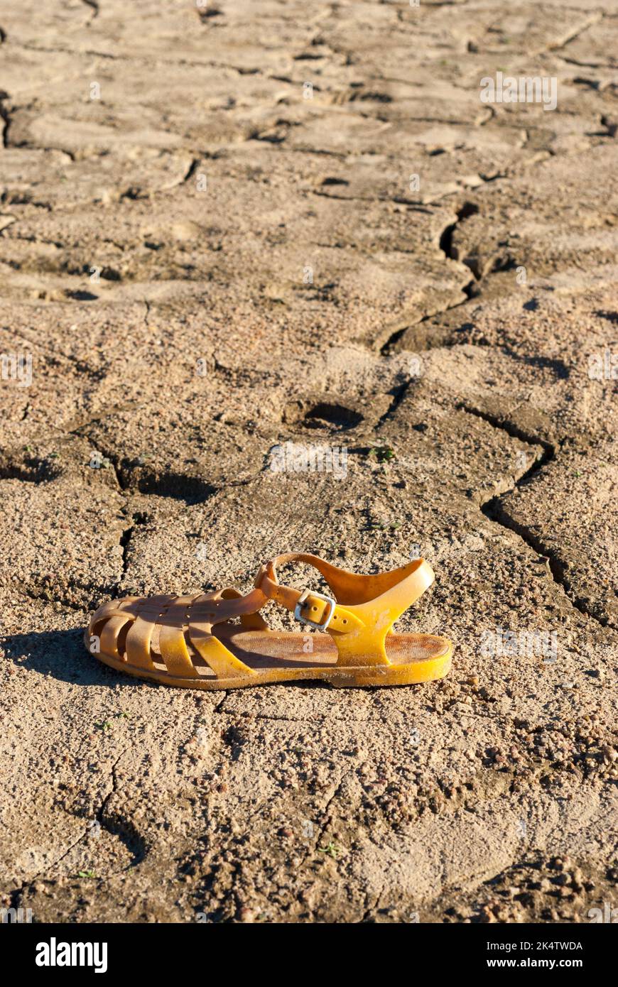 Plastikkrabben Sandale auf gerissene Erde aufgrund des Mangels an Wasser Klimawandel Dürre Stockfoto