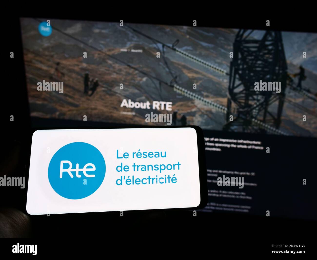 Person mit Mobiltelefon und Logo von Reseau de Transport d'Electricite S.A. (RTE) auf dem Bildschirm vor der Webseite. Konzentrieren Sie sich auf die Telefonanzeige. Stockfoto