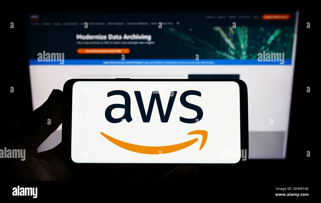 Person, die das Smartphone mit dem Logo des US-Cloud-Unternehmens Amazon Web Services Inc. (AWS) auf dem Bildschirm vor der Website hält. Konzentrieren Sie sich auf die Telefonanzeige. Stockfoto