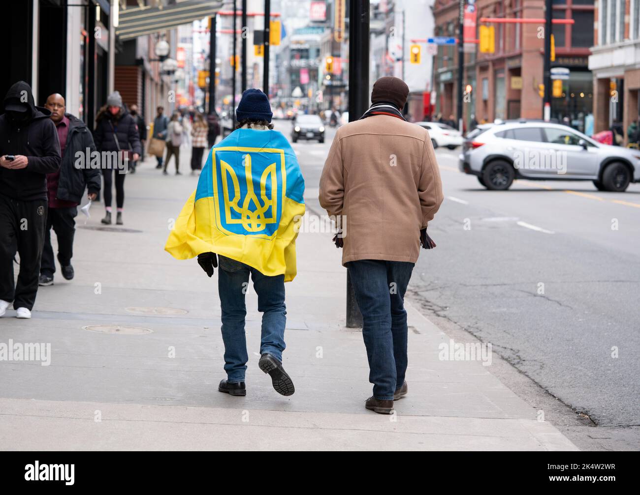 Mann, der 2022 in Toronto, Ontario, Kanada, die Straße entlang ging und eine ukrainische Flagge wekte. Zwei Männer marschieren solidarisch auf der ukrainischen Kundgebung Stockfoto