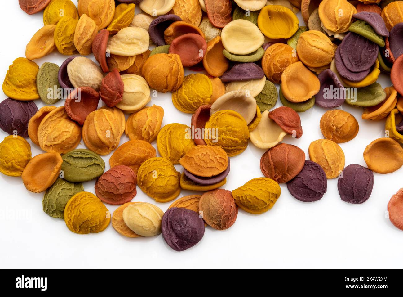Bunte Olecchiette-Pasta, italienische Hartweizengrieß-Pasta mit Kurkuma, Spinat, Rote Beete und schwarzer Karotte, isoliert auf Weiß Stockfoto