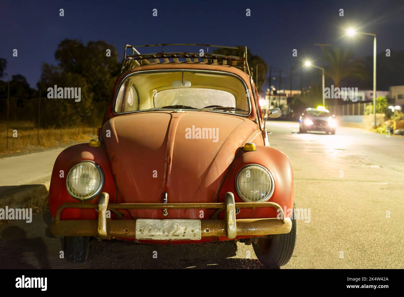 Ein alter Volkswagen oder VW Käfer parkte nachts auf dem Roadhouse. Es gibt niemanden mit dem klassischen alten Auto und es wird von nahe gelegenen Straßenlaternen beleuchtet Stockfoto