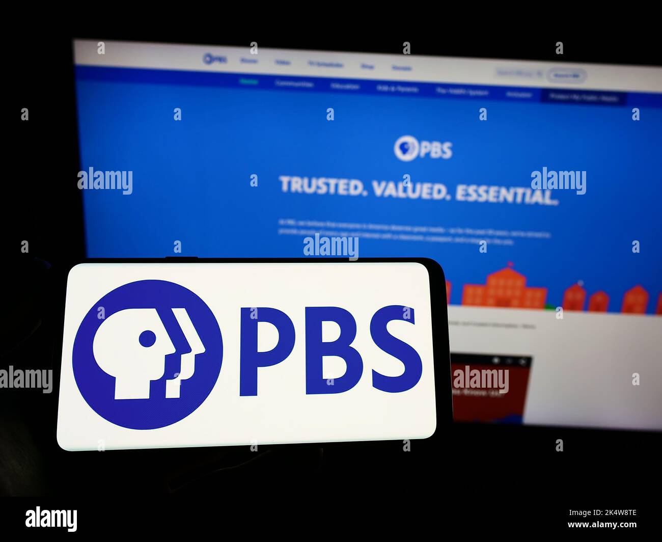 Person, die das Smartphone mit dem Logo des US-fernsehsenders Public Broadcasting Service (PBS) auf dem Bildschirm vor der Website hält. Konzentrieren Sie sich auf die Telefonanzeige. Stockfoto