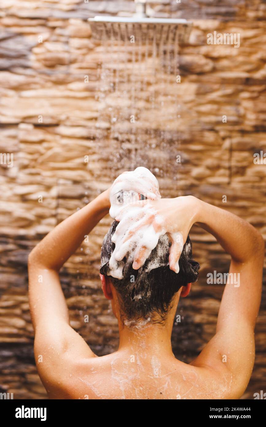 Glückliche Birazialfrau, die duscht und im Badezimmer Haare wäscht Stockfoto