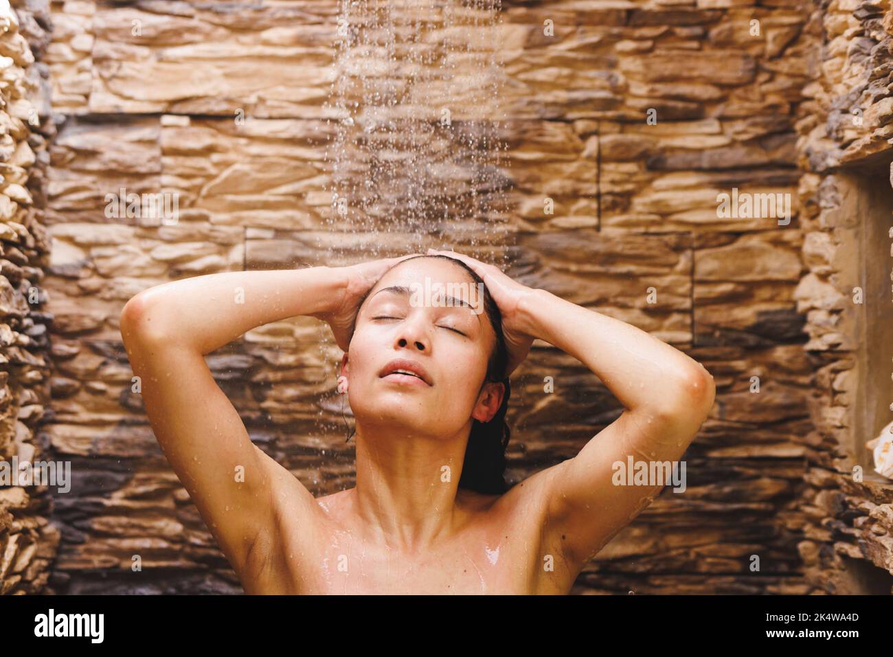 Glückliche Birazialfrau, die duscht und im Badezimmer Haare wäscht Stockfoto