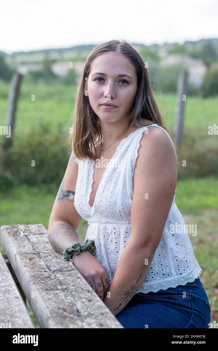 Porträt einer Frau, die im Sommer an einem Gartentisch sitzt, Frankreich Stockfoto