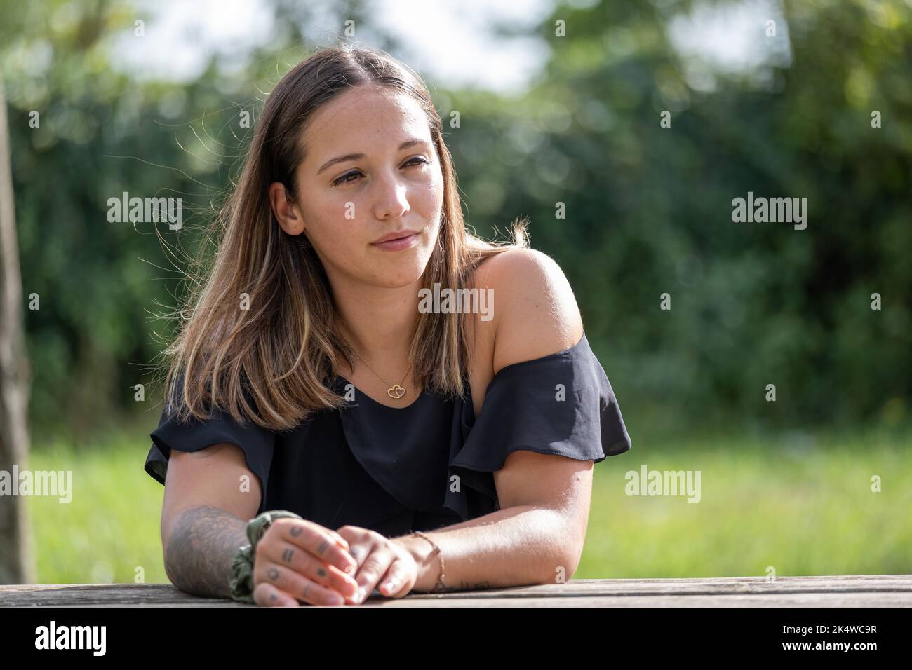 Porträt einer jungen Frau, die sich im Sommer auf einen Holzzaun stützt Stockfoto