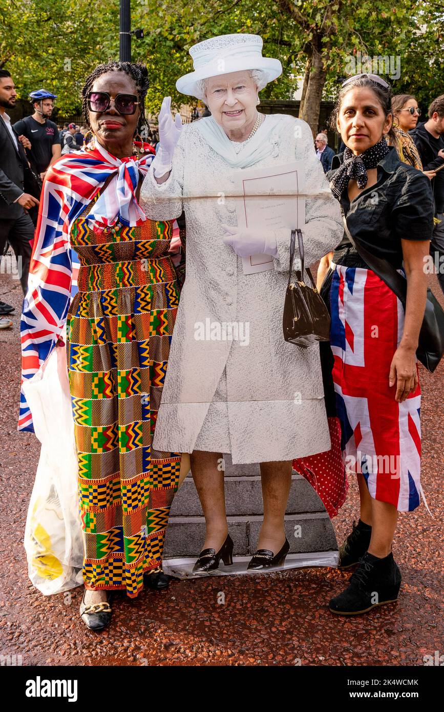 Der Tag nach dem Tod von Königin Elizabeth II zwei Frauen tragen In Tribute, The Mall, London, Großbritannien, Einen lebensgroße Karton-Ausschnitt aus der Queen. Stockfoto