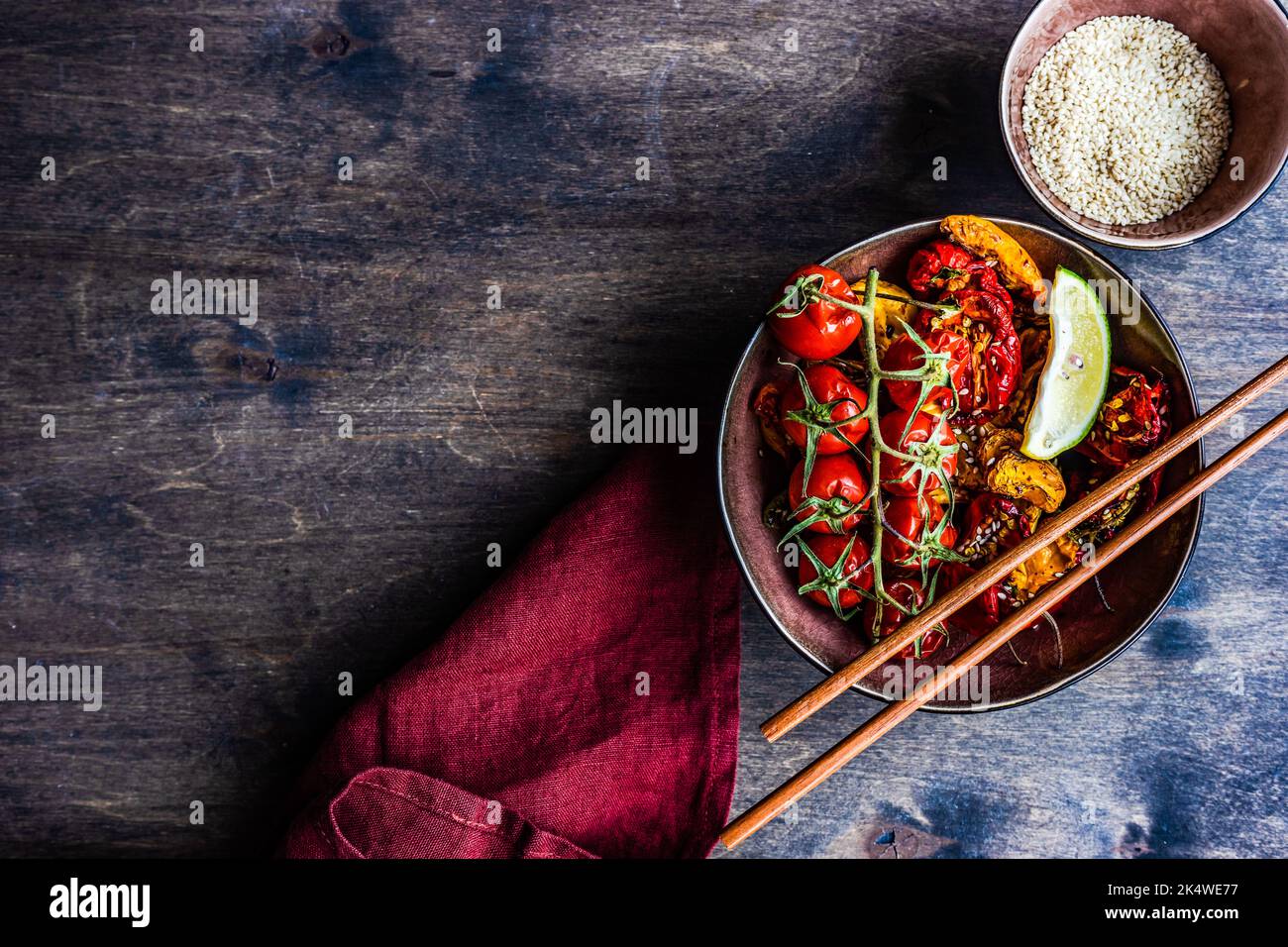 Ansicht von oben auf eine Schüssel mit asiatisch gerösteter Chilischote und Tomaten mit Sesam Stockfoto