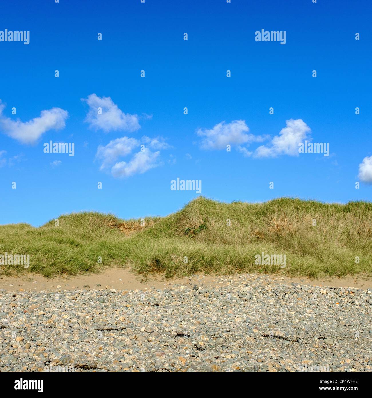 Weiße Wolken in einem klaren blauen Himmel über den Sanddünen bei Rhoseigr, North Wales, Großbritannien Stockfoto