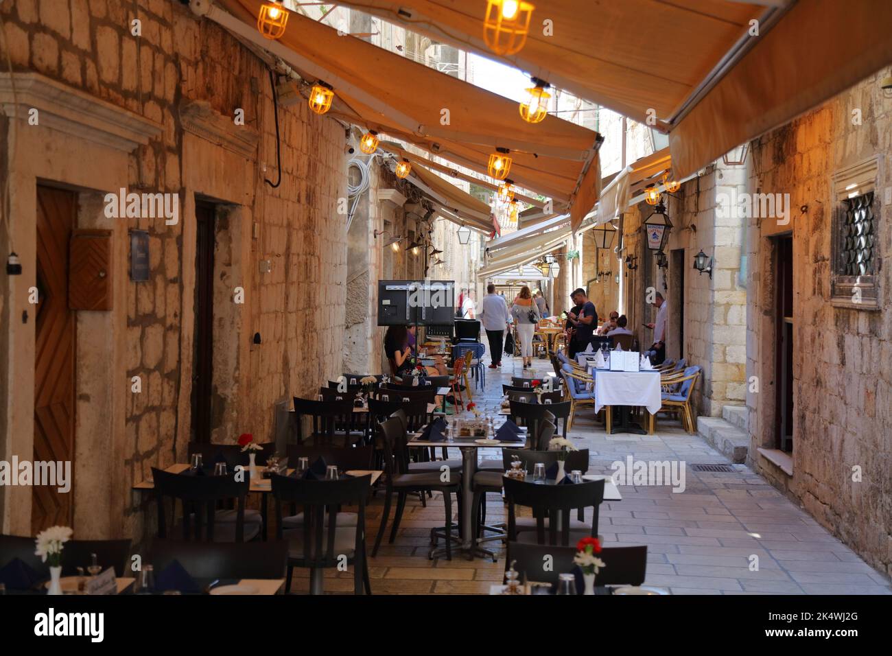 DUBROVNIK, KROATIEN - 18. JULI 2021: Touristen enge Straßen und schattige Restaurants der mittelalterlichen Altstadt von Dubrovnik, ein UNESCO-Weltkulturerbe Stockfoto