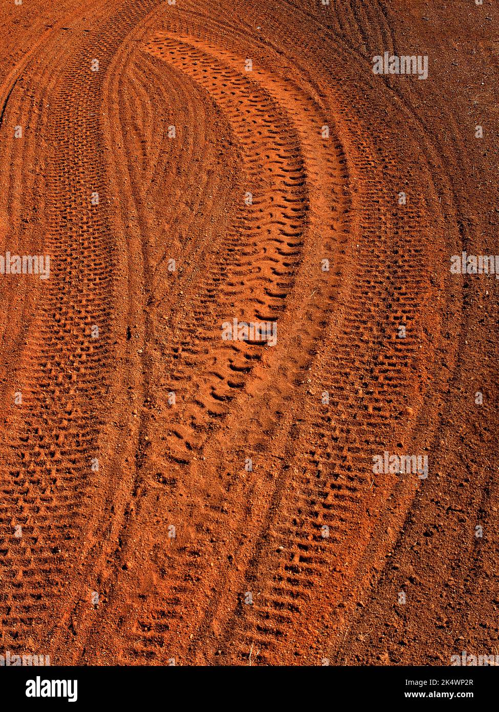Mehrere Reifenspuren im weichen braunen Schmutz, die auf dem Boden fahren Stockfoto