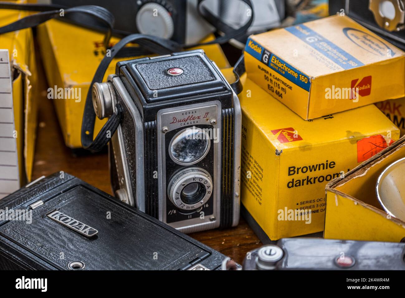 Eine alte Kodak Spiegelreflexkamera in der Mitte, die von anderen Kodak-Zubehörteilen umgeben ist, und eine Teilansicht anderer Kameras, die alle zusammen gruppiert sind Stockfoto