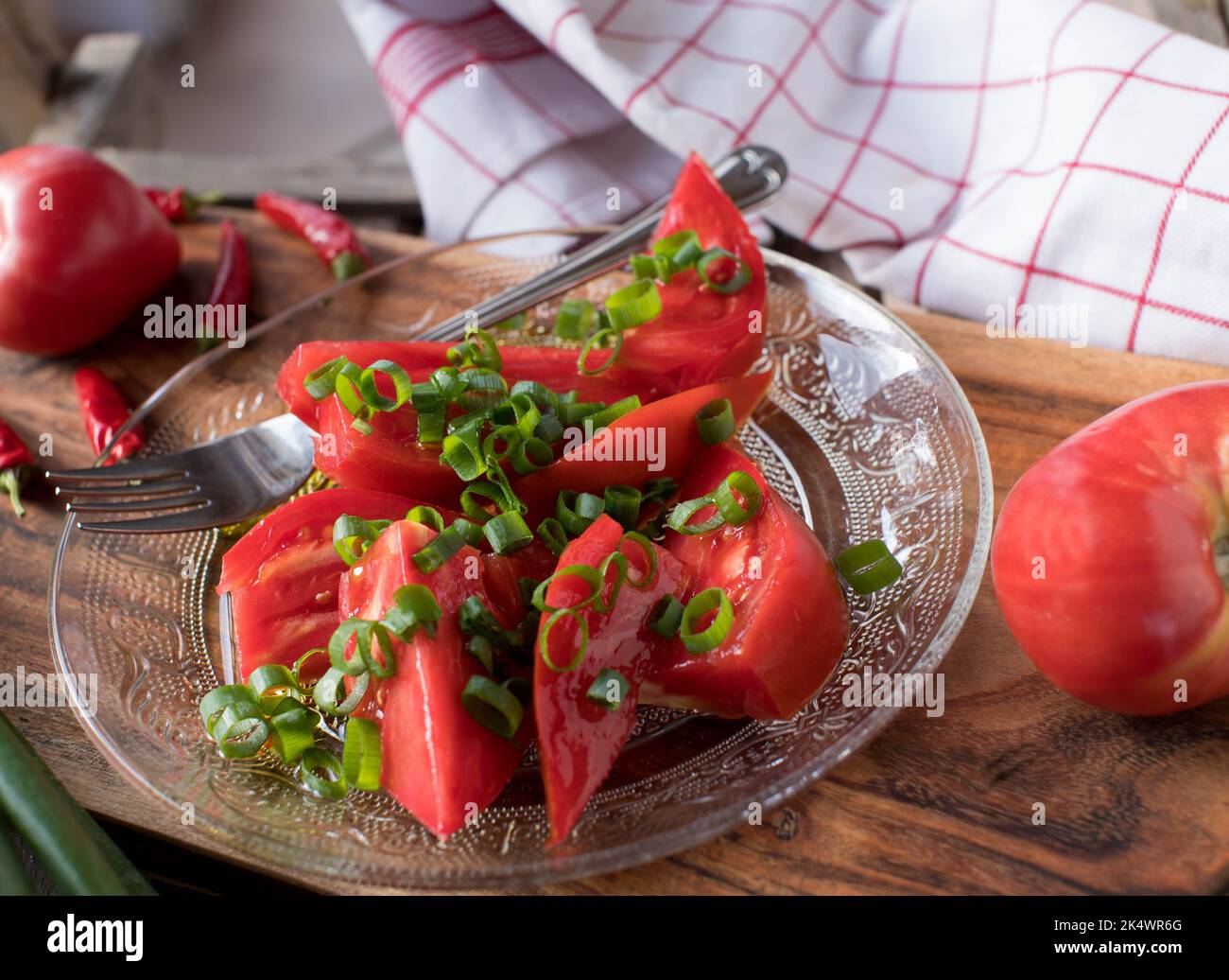 Salat mit Rindertomate und Schnittlauch und Olivenöl auf einem Teller Stockfoto