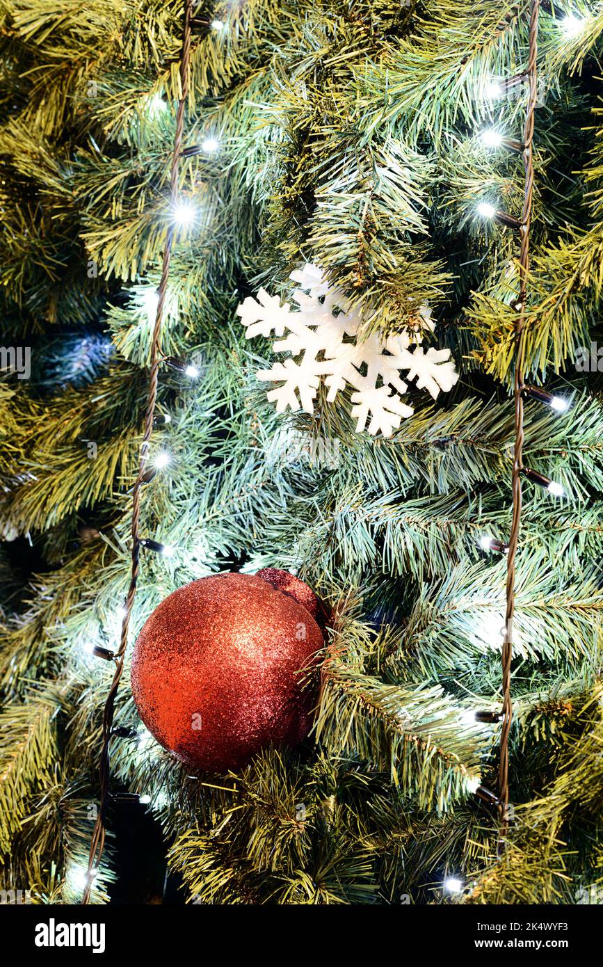 Weihnachtshintergrund mit Weihnachtsbaumschmuck. Detail mit Lichtern, Kugeln und anderen Dekorationen eines Weihnachtsbaums. Stockfoto