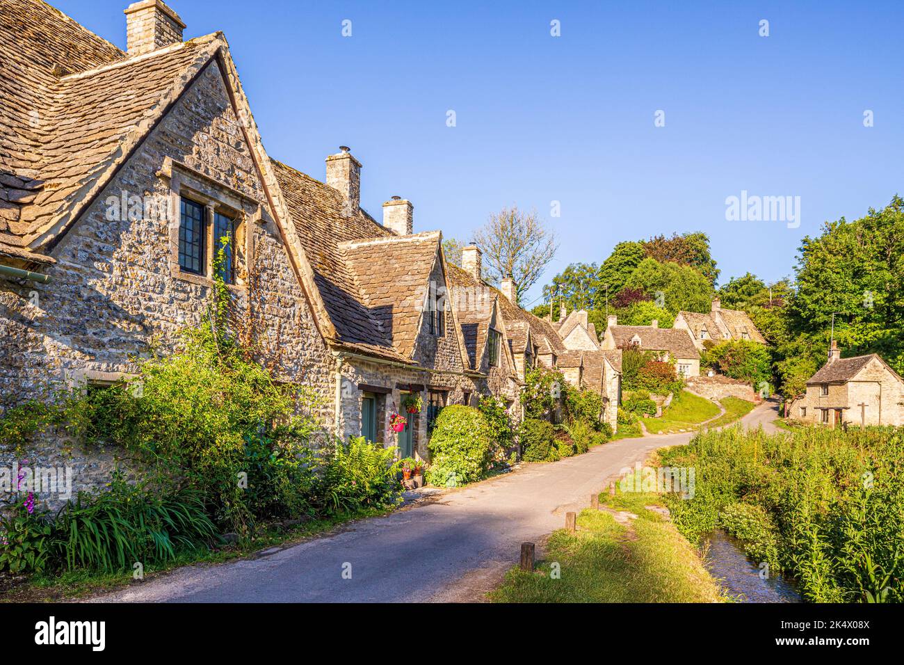 Im Hochsommerlicht am frühen Morgen in der Arlington Row im Cotswold-Dorf Bibury, Gloucestershire, England Stockfoto