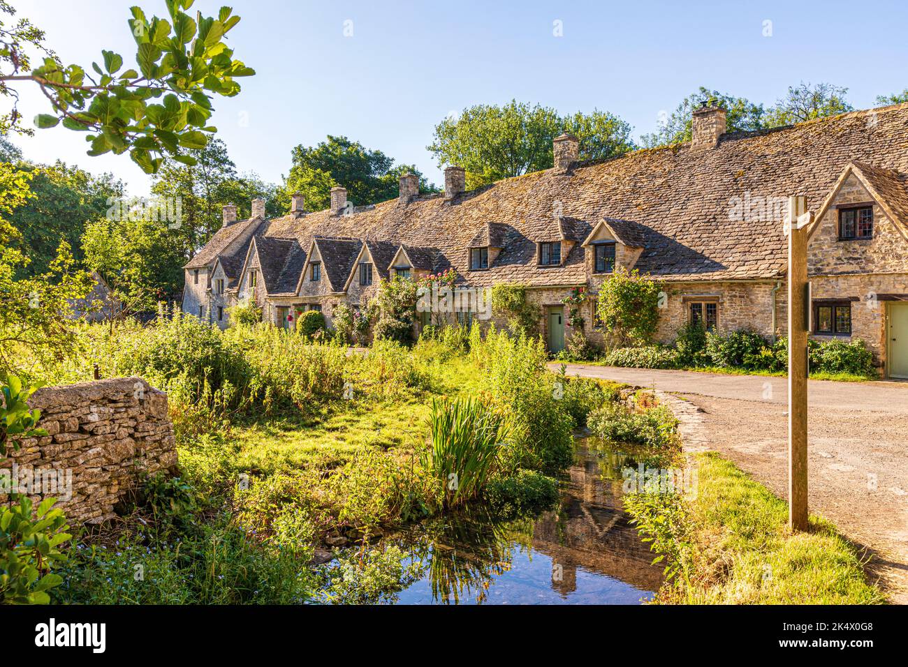 Im Hochsommerlicht am frühen Morgen in der Arlington Row im Cotswold-Dorf Bibury, Gloucestershire, England Stockfoto